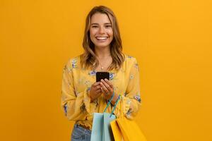 beautiful attractive smiling woman in yellow shirt and jeans holding shopping bags photo