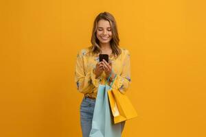 beautiful attractive smiling woman in yellow shirt and jeans holding shopping bags photo