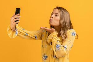 beautiful attractive smiling woman in yellow shirt holding smartphone photo