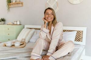 bonito sonriente mujer relajante a hogar en cama en Mañana en pijama foto