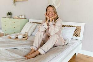 bonito sonriente mujer relajante a hogar en cama en Mañana en pijama foto