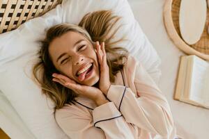 pretty smiling woman relaxing at home on bed in morning in pajamas photo