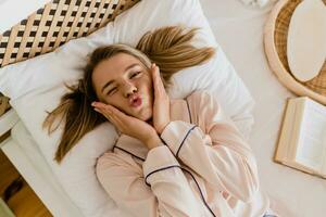 pretty smiling woman relaxing at home on bed in morning in pajamas photo