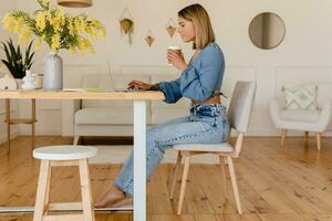 joven bonito elegante mujer trabajando remoto a hogar a mesa lugar de trabajo, estudiante educación foto