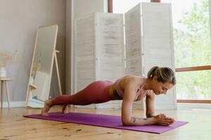 hermosa atlético mujer en haciendo yoga a hogar, sano estilo de vida foto