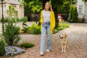 happy smiling woman in yellow sweater walking at her house with a dog golden retriever photo