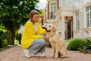 happy smiling woman in yellow sweater walking at her house with a dog golden retriever photo