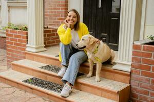 happy smiling woman in yellow sweater walking at her house with a dog golden retriever photo