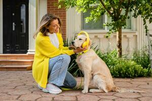 woman in yellow sweater walking at her house with a dog listening to music in headphones photo