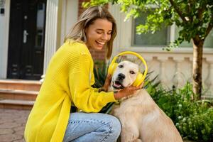 woman in yellow sweater walking at her house with a dog listening to music in headphones photo