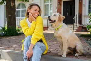 contento sonriente mujer en amarillo suéter caminando a su casa con un perro dorado perdiguero foto