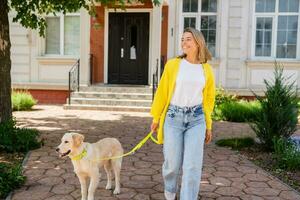 happy smiling woman in yellow sweater walking at her house with a dog golden retriever photo