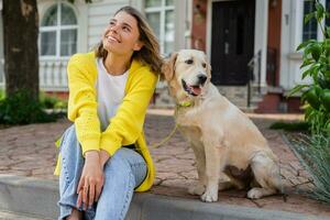 happy smiling woman in yellow sweater walking at her house with a dog golden retriever photo
