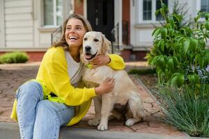 happy smiling woman in yellow sweater walking at her house with a dog golden retriever photo