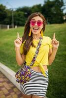 young stylish woman having fun in city park, summer style fashion trend photo