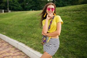 young stylish woman having fun in city park, summer style fashion trend photo
