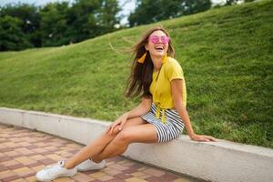 young stylish woman having fun in city park, summer style fashion trend photo