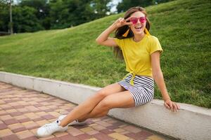 young stylish woman having fun in city park, summer style fashion trend photo