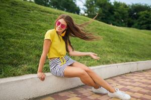 young stylish woman having fun in city park, summer style fashion trend photo