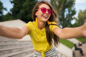 young stylish woman having fun in city park, summer style fashion trend photo