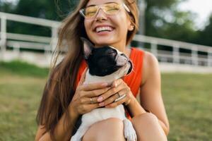 young happy smiling woman in orange dress having fun playing with dog in park photo