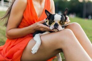 young happy smiling woman in orange dress having fun playing with dog in park photo