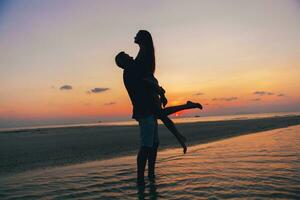 joven Pareja en amor en puesta de sol en playa, teniendo divertido, siluetas, verano vacaciones foto