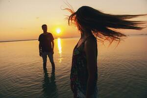 joven Pareja en amor en puesta de sol en playa, teniendo divertido, siluetas, verano vacaciones foto