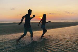 joven Pareja en amor en puesta de sol en playa, teniendo divertido, siluetas, verano vacaciones foto