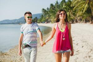 young beautiful couple walking on tropical beach photo