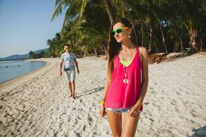 young beautiful couple walking on tropical beach photo