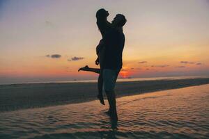 joven Pareja en amor en puesta de sol en playa, teniendo divertido, siluetas, verano vacaciones foto