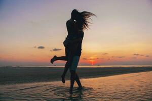 joven Pareja en amor en puesta de sol en playa, teniendo divertido, siluetas, verano vacaciones foto