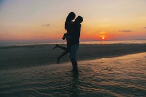 joven Pareja en amor en puesta de sol en playa, teniendo divertido, siluetas, verano vacaciones foto