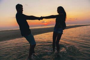 joven Pareja en amor en puesta de sol en playa, teniendo divertido, siluetas, verano vacaciones foto