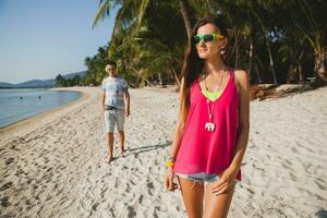 young beautiful couple walking on tropical beach photo
