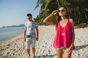 young beautiful couple walking on tropical beach photo