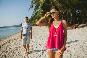 young beautiful couple walking on tropical beach photo