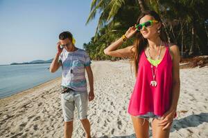 young beautiful couple walking on tropical beach photo
