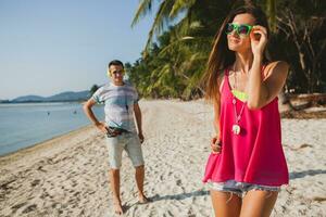 young beautiful couple walking on tropical beach photo