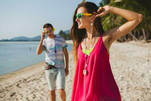 young beautiful couple walking on tropical beach photo
