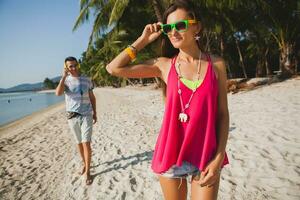 young beautiful couple walking on tropical beach photo