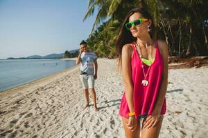 young beautiful couple walking on tropical beach photo
