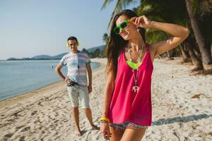 young beautiful couple walking on tropical beach photo