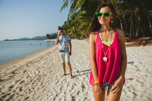 young beautiful couple walking on tropical beach photo