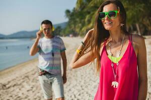 young beautiful couple walking on tropical beach photo