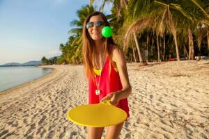 young hipster woman playing ping-pong on tropical beach, summer vacation. photo