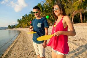 young beautiful couple in love playing ping pong on tropical beach photo