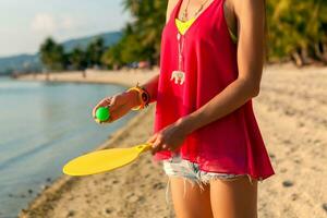 young hipster woman playing ping-pong on tropical beach, summer vacation. photo