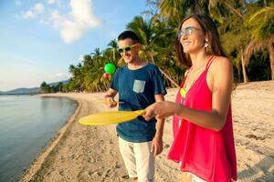 young beautiful couple in love playing ping pong on tropical beach photo